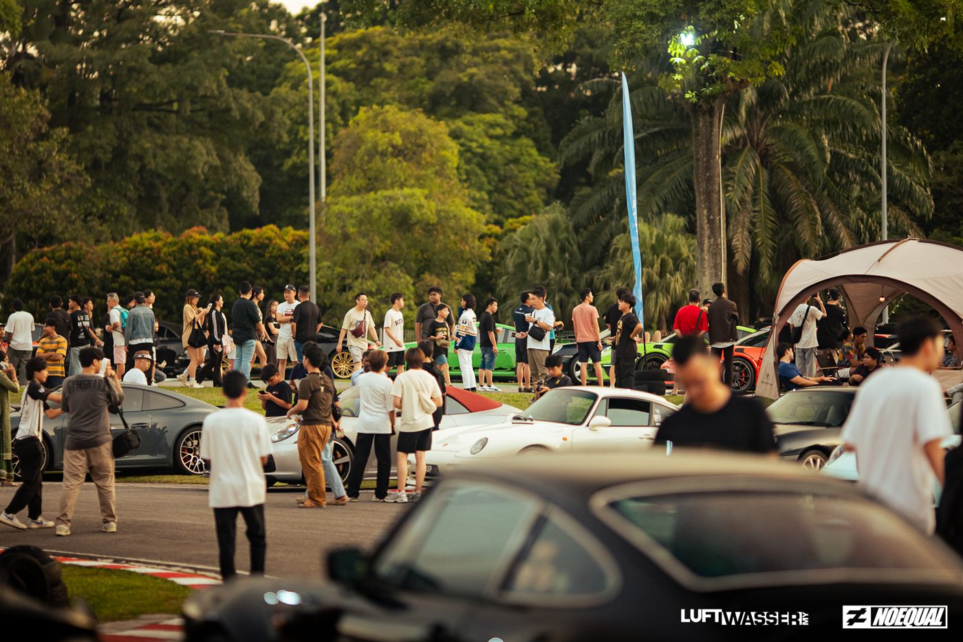 Visitors gathered among the cars and tents as the sun drops